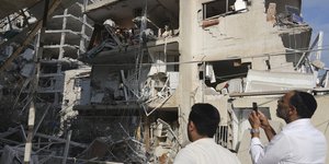 Δύο άνδρες μπροστά από ένα κατεστραμμένο κτίριο που χτυπήθηκε από πύραυλο που εκτοξεύτηκε από το Ιράν, κοντά στο Τελ Αβίβ, Κυριακή 15 Ιουνίου 2025 