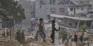 Παιδιά σε κοιμητήριο στη Γάζα με φόντο συντρίμμια