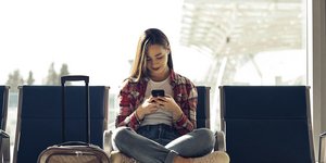Γυναίκα κοιτάει το κινητό της στο αεροδρόμιο