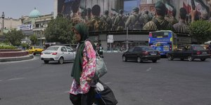Γυναίκα περπατά στην Τεχεράνη, με φόντο μεγάλο στρατιωτικό banner