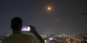 Ένας άνδρας τραβάει φωτογραφία με κινητό τηλέφωνο καθώς πύραυλοι που εκτοξεύονται από το Ιράν προς το Ισραήλ πετούν πάνω από συριακό έδαφος στη Δαμασκό της Συρίας, τα ξημερώματα της Τετάρτης 18 Ιουνίου 2025