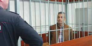 O Λεβ Σλόσμπεργκ κοιτάζει αστυνομικό πίσω από κάγκελα