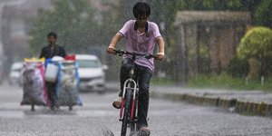 Παιδί στο Πακιστάν κάνει ποδήλατο υπό βροχή