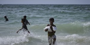 Παιδιά βγάζουν από τη θάλασσα σακιά με ανθρωπιστική βοήθεια που έπεσαν από τα αεροσκάφη