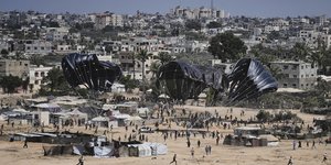 Παλαιστίνιοι στη Γάζα τρέχουν να συλλέξουν την ανθρωπιστική βοήθεια που πέφτει με αλεξίπτωτα από αεροπλάνα
