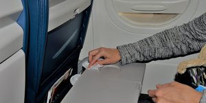 Γυναίκα καθαρίζει τραπεζάκι αεροπλάνου