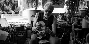 Ο Παντελής Μελισσινός κρατά στα χέρια του και φτιάχνει ένα σανδάλι