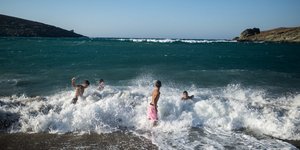 Παιδιά παίζουν με τα κύματα σε παραλία της Τήνου