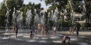 Children play with the water on a fountain