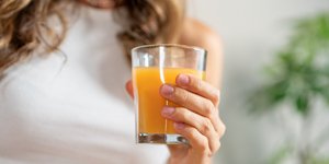 Γυναίκα κρατά ποτήρι με φυσικό χυμό πορτοκάλι