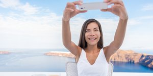 Γυναίκα ποζάρει με φόντο την Καλντέρα