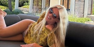 Χαμογελαστή η Κλόντια Σίφερ, ποζάρει σε καναπέ κάτω από κιόσκι