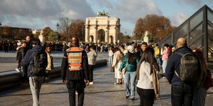 Εργαζόμενος σε ιδιωτική εταιρεία ασφάλειας στο προαύλιο του Λούβρου, μαζί με επισκέπτες
