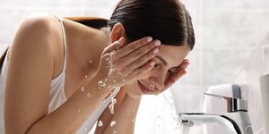 Γυναίκα πλένει το πρόσωπό της με νερό
