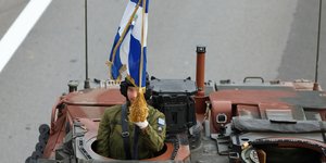 Στρατιώτης κρατά την ελληνική σημαία μέσα από τανκ