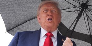 Ο Αμερικανός πρόεδρος Ντόναλντ Τραμπ με ομπρέλα πριν επιβιβαστεί στο Air Force One