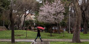 Μια γυναίκα με ομπρέλα περπατά στη βροχή