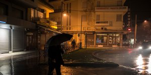 Άνδρας με ομπρέλα περπατά στη βροχή το βράδυ