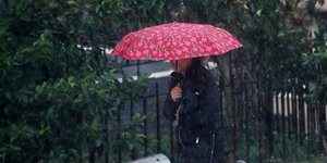 Γυναίκα κρατάει ομπρέλα για να προστατευτεί από τη βροχή 