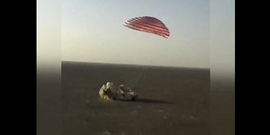 Κρεμασμένη από ένα τεράστιο αλεξίπτωτο στα χρώματα του κόκκινου και του λευκού, η διαστημική κάψουλα