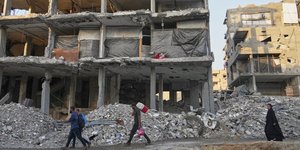 Κάτοικοι στη Γάζα περπατούν δίπλα σε κατεστραμένο σπίτι που όμως κατοικείται 