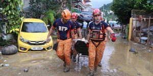 Διασώστες στις Φιλιππίνες μεταφέρουν ανάπηρο άτομο μέσα στις λάσπες μετά το πέρασμα του κυκλώνα Καλμαέγκι