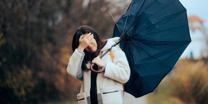 Γυναίκα κρατάει ομπρέλα που έχει σπάσει