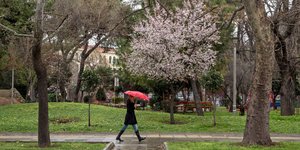 Μια γυναίκα με ομπρέλα περπατά στη βροχή