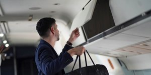 Επιβάτης βάζει την τσάντα του στα ντουλαπάκια του αεροπλάνου