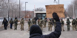 Ατομο κρατά πλακάτ μπροστά από αστυνομικούς του ICE