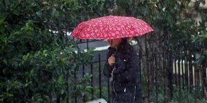 Γυναίκα κρατάει ομπρέλα για να προστατευτεί από τη βροχή 