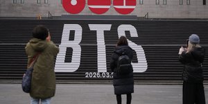 Πεζοί σταματούν για να τραβήξουν φωτογραφίες στα τεράστια γράμματα του συγκροτήματος K-pop BTS στο κέντρο της Σεούλ – Φωτ: ΑΡ