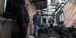 Κάτοικοι επιθεωρούν καμένο σπίτι σε χωριό στη Δυτική Όχθη