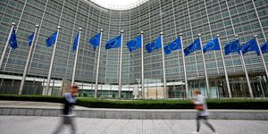 Σημαίες της Ευρωπαϊκής Ένωσης κυματίζουν ενώ πεζοί περπατούν μπροστά από την έδρα της ΕΕ στις Βρυξέλλες 