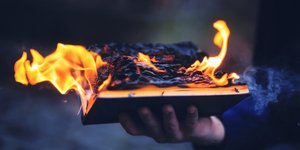 Ιερό βιβλίο καίγεται στο χέρι ιερέα Φωτ: Shutterstock