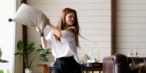 νεαρή γυναίκα θυμωμένη με μαξιλάρι στα χέρια