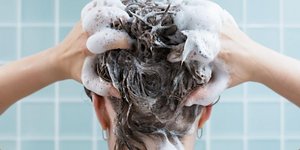 γυναίκα λούζει τα μαλλιά της με σαμπουάν και αποφεύγει την τριχόπτωση