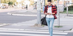 Πεζός διασχίζει διάβαση κρατώντας κινητό τηλέφωνο
