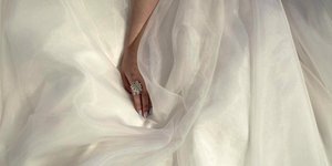 κοντινό σε χέρι νύφης πάνω σε λευκό νυφικό.