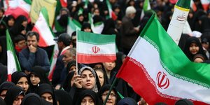 Ιρανοί, μεταξύ αυτών και γυναίκες, κρατούν σημαίες του Ιράν και στέκονται στο πλευρό του καθεστώτος 