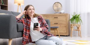 Κορίτσι που κάθεται στο πάτωμα με κινητό