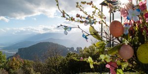 Easter landscape in Meteora, Greece. Flowers with coloured easter eggs bouquet near church bell - Shutterstock