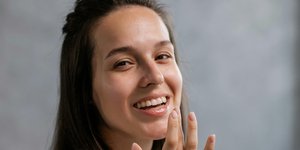 νέα γυναίκα με λευκό t-shirt που φοράει προϊόν χειλιών