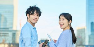 Χαμογελαστοί άνδρας και γυναίκα από την Ιαπωνία με κινητά τηλέφωνα στα χέρια