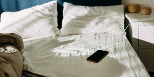 Φόρτιση κινητού τηλεφώνου πάνω στο κρεβάτι 