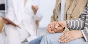 Ζευγάρι κρατιέται από το χέρι μπροστά σε γιατρό