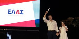 Ο Αλέξης Τσίπρας με το κοριτσάκι και το λογότυπο του κόμματος