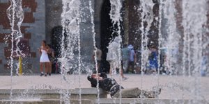 Μια γυναίκα δροσίζεται σε ένα σιντριβάνι στο κέντρο του Μιλάνου