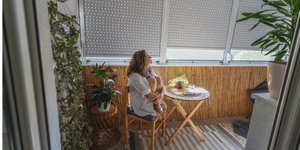 Γυναίκα κάθεται με κλειστά παντζούρια