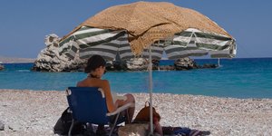 Γυναίκα διαβάζει βιβλίο στην παραλία